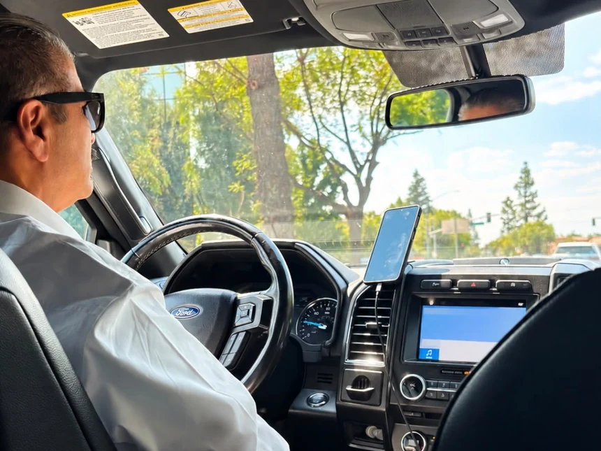 Professional chauffeur in a white shirt driving through Bakersfield