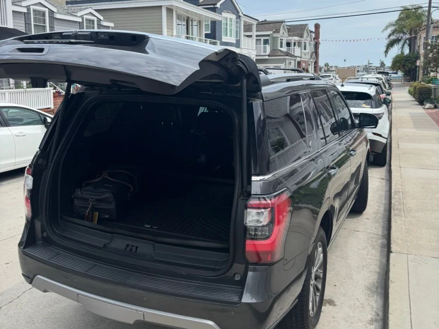 Luxury SUV with the tailgate open and luggage loaded on a coastal street