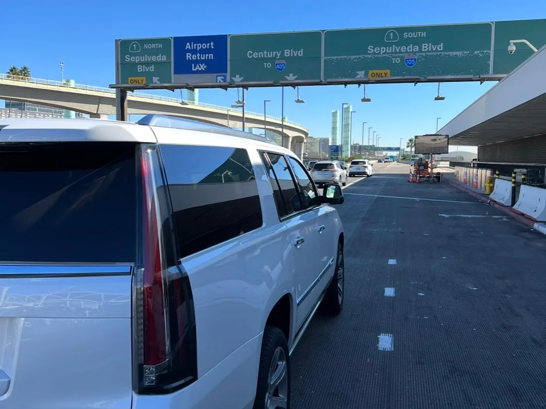 White luxury SUV at the LAX airport return lane with Sepulveda Blvd and Century Blvd signage overhead