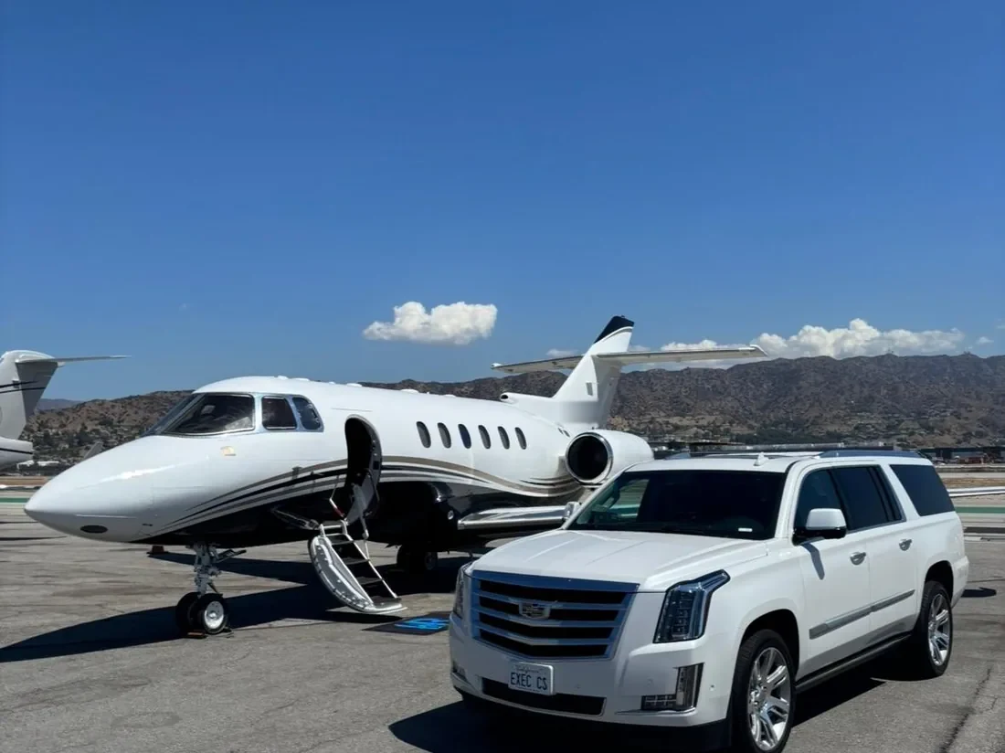 White luxury SUV from Executive Car Service parked beside a private jet on the tarmac, EXEC CS plate visible