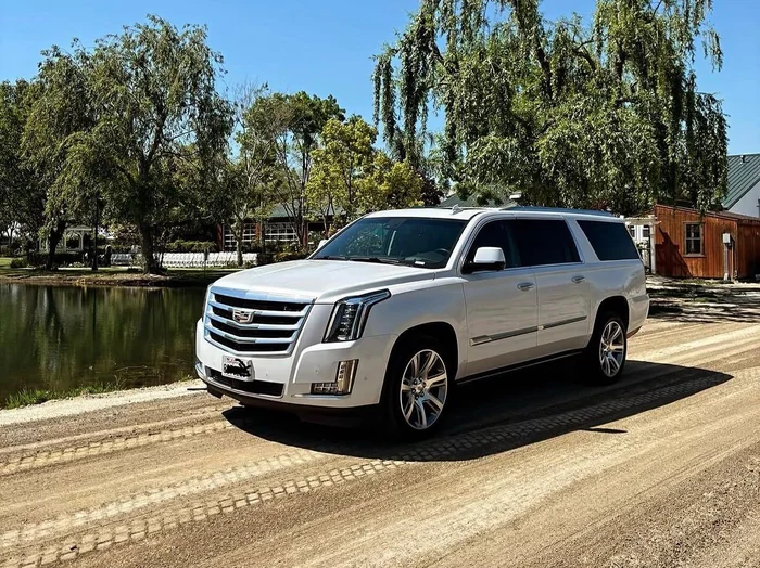 White luxury SUV at a wedding venue with the ceremony chairs set out by the pond